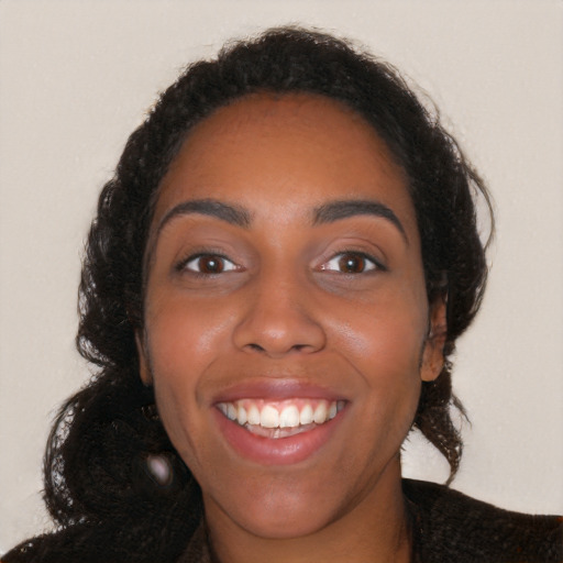 Joyful black young-adult female with long  brown hair and brown eyes