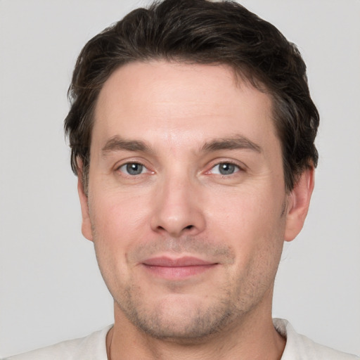 Joyful white young-adult male with short  brown hair and grey eyes