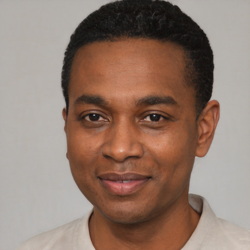Joyful black young-adult male with short  black hair and brown eyes