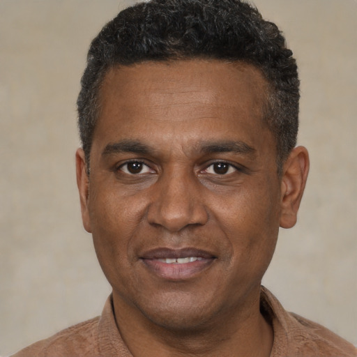 Joyful black adult male with short  black hair and brown eyes