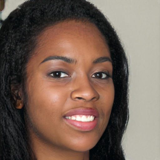 Joyful black young-adult female with long  brown hair and brown eyes