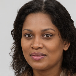 Joyful black young-adult female with long  brown hair and brown eyes