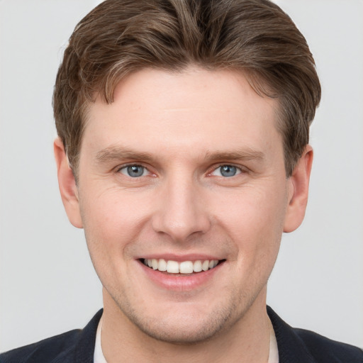 Joyful white young-adult male with short  brown hair and grey eyes