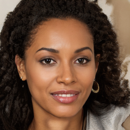 Joyful black young-adult female with long  brown hair and brown eyes