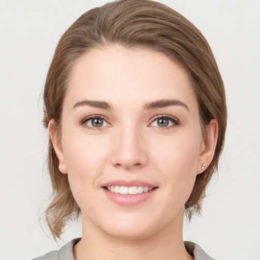 Joyful white young-adult female with medium  brown hair and grey eyes