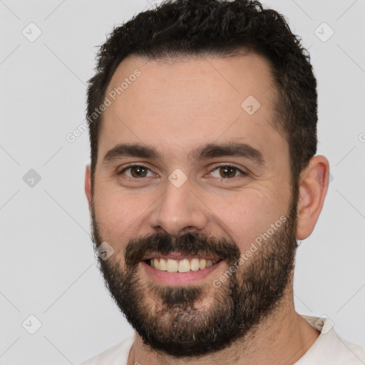 Joyful white young-adult male with short  black hair and brown eyes