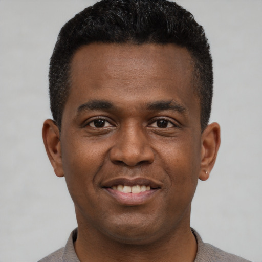 Joyful black young-adult male with short  black hair and brown eyes
