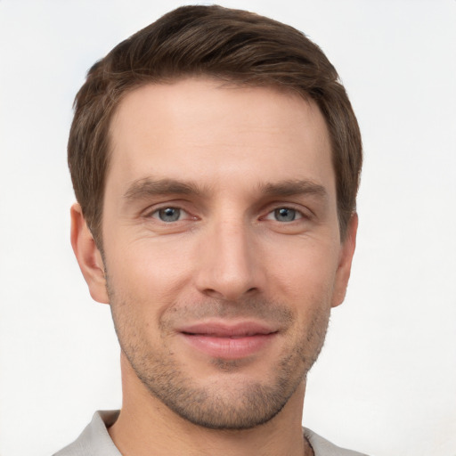 Joyful white young-adult male with short  brown hair and grey eyes