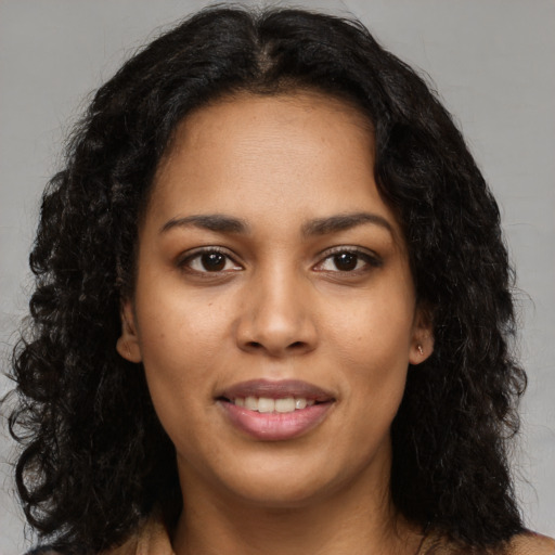 Joyful black young-adult female with long  brown hair and brown eyes
