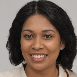 Joyful black young-adult female with long  brown hair and brown eyes