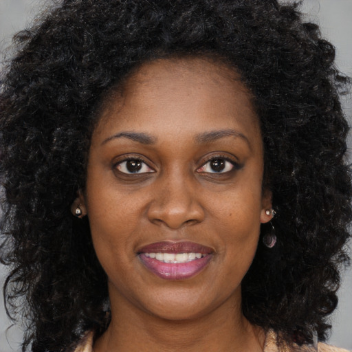 Joyful black young-adult female with long  brown hair and brown eyes