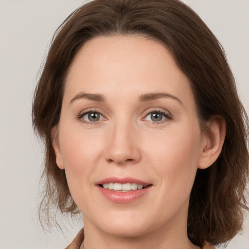 Joyful white young-adult female with medium  brown hair and grey eyes