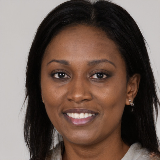Joyful black young-adult female with long  brown hair and brown eyes