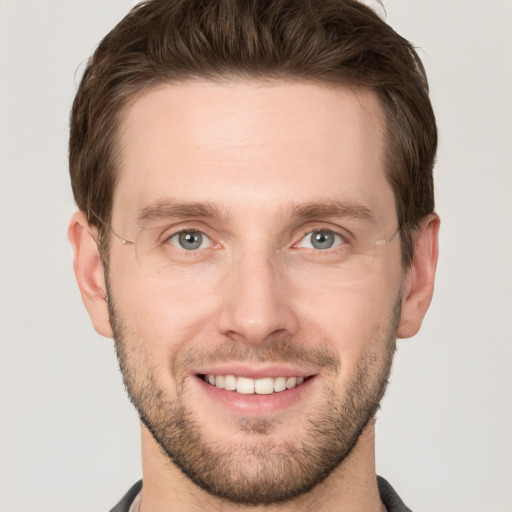 Joyful white young-adult male with short  brown hair and grey eyes