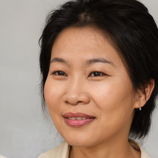 Joyful asian adult female with medium  brown hair and brown eyes