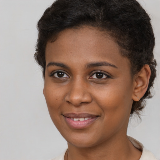 Joyful black young-adult female with short  brown hair and brown eyes
