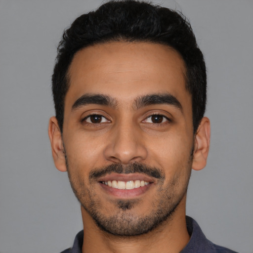 Joyful latino young-adult male with short  black hair and brown eyes