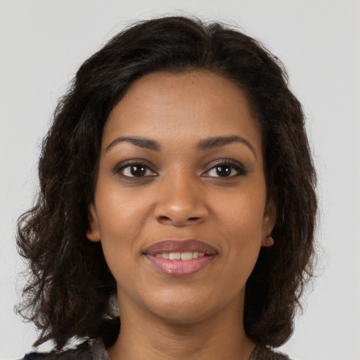 Joyful black young-adult female with long  brown hair and brown eyes