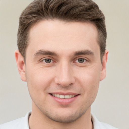 Joyful white young-adult male with short  brown hair and grey eyes