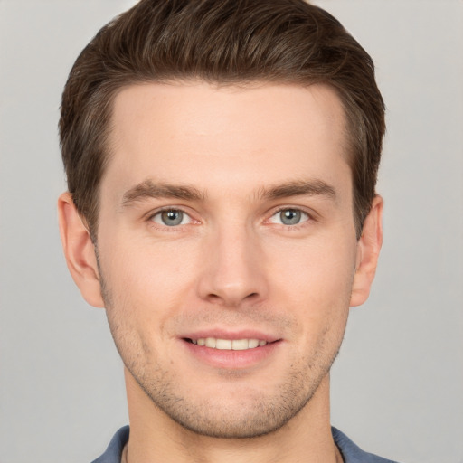 Joyful white young-adult male with short  brown hair and grey eyes