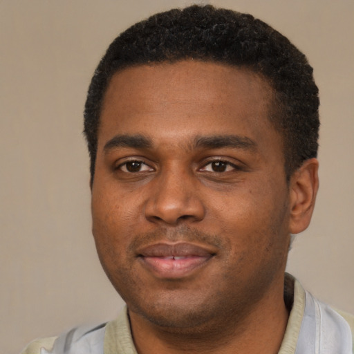 Joyful black young-adult male with short  black hair and brown eyes