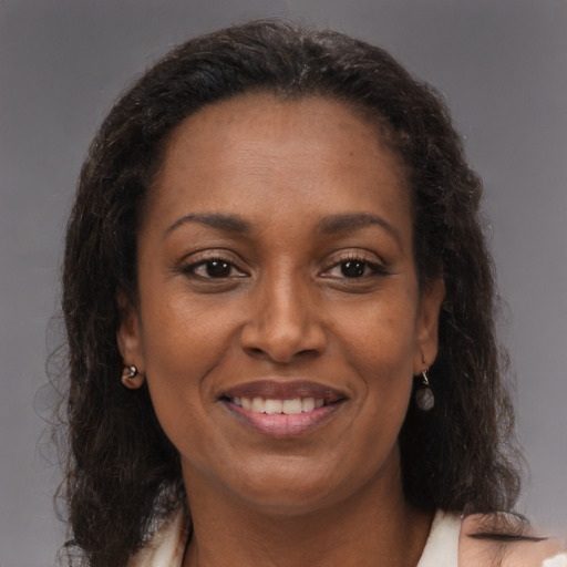 Joyful black adult female with long  brown hair and brown eyes