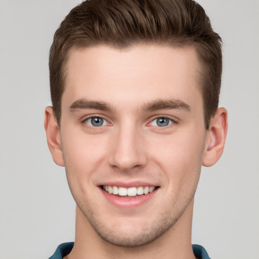 Joyful white young-adult male with short  brown hair and grey eyes