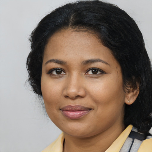 Joyful black young-adult female with long  brown hair and brown eyes