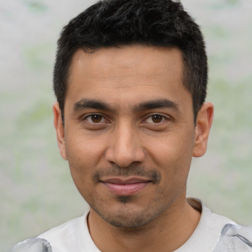 Joyful latino young-adult male with short  black hair and brown eyes