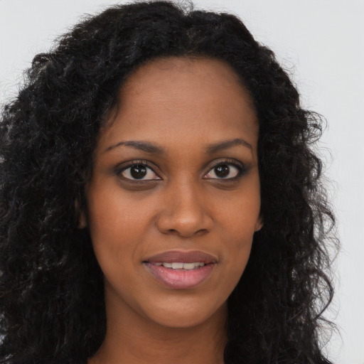 Joyful black young-adult female with long  brown hair and brown eyes