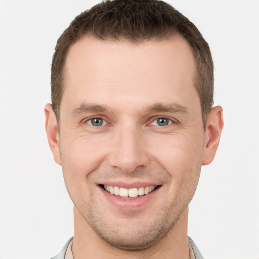 Joyful white young-adult male with short  brown hair and grey eyes