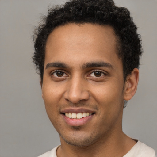 Joyful black young-adult male with short  brown hair and brown eyes