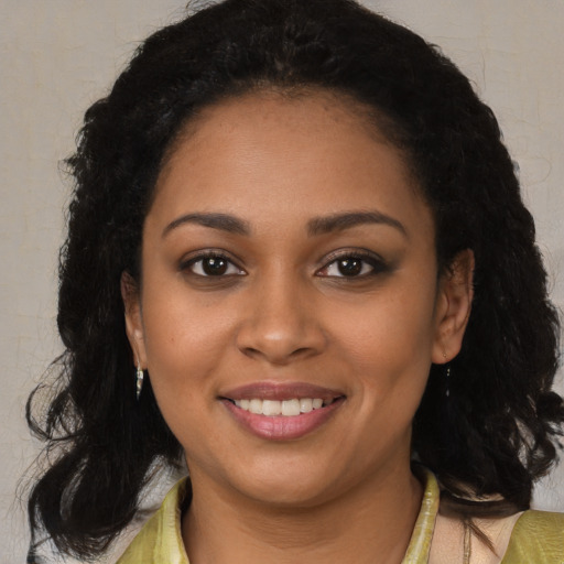 Joyful black young-adult female with long  brown hair and brown eyes