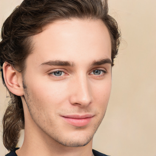 Joyful white young-adult male with long  brown hair and brown eyes