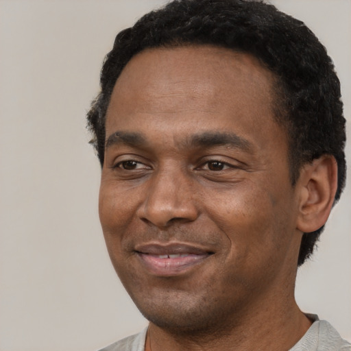 Joyful black young-adult male with short  black hair and brown eyes