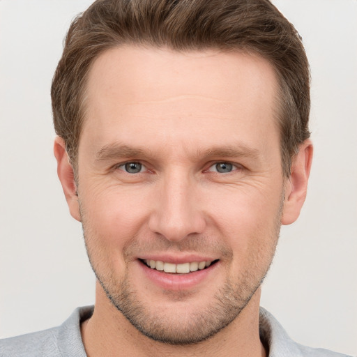 Joyful white young-adult male with short  brown hair and grey eyes