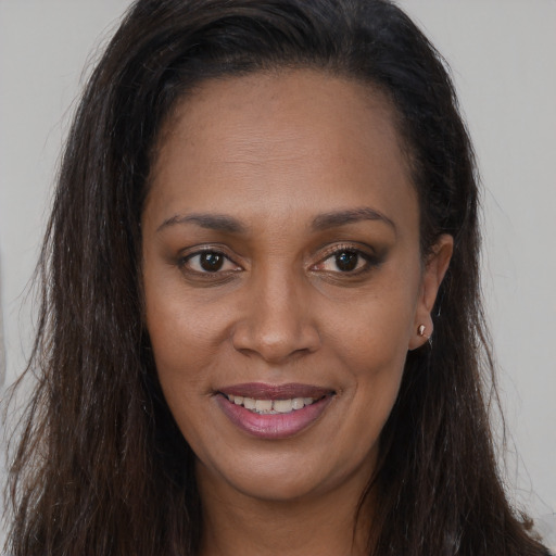 Joyful black young-adult female with long  brown hair and brown eyes
