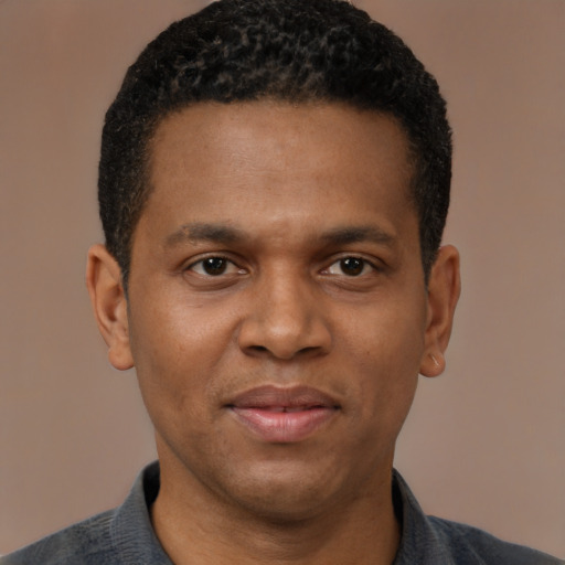 Joyful black young-adult male with short  brown hair and brown eyes