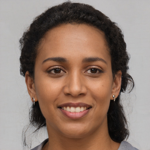 Joyful black young-adult female with long  brown hair and brown eyes
