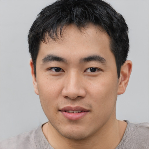 Joyful asian young-adult male with short  black hair and brown eyes