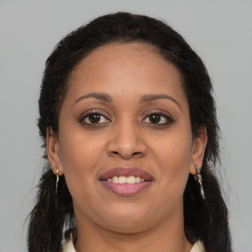 Joyful black young-adult female with long  brown hair and brown eyes