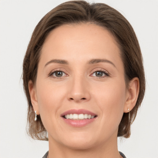 Joyful white young-adult female with medium  brown hair and grey eyes