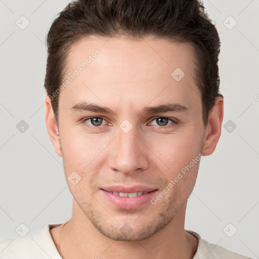 Joyful white young-adult male with short  brown hair and grey eyes