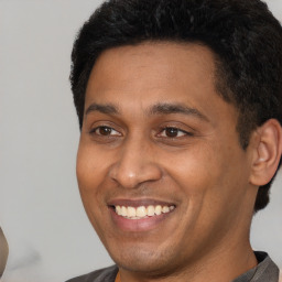Joyful latino young-adult male with short  brown hair and brown eyes