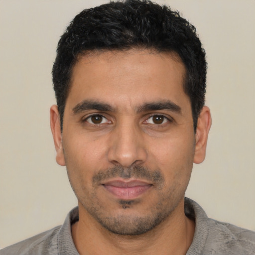 Joyful latino young-adult male with short  black hair and brown eyes