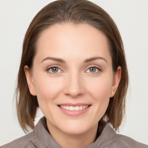 Joyful white young-adult female with medium  brown hair and grey eyes