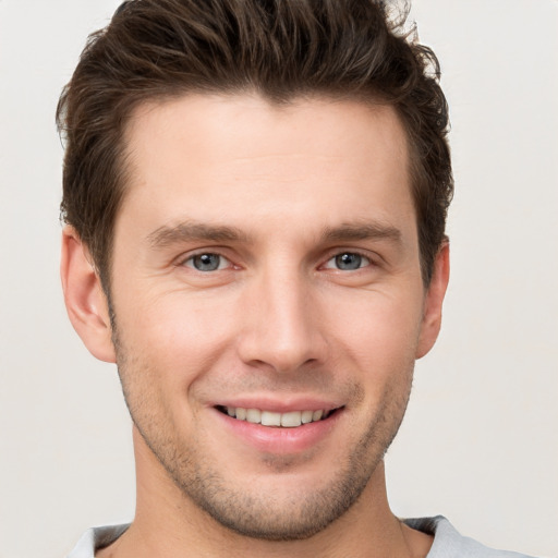 Joyful white young-adult male with short  brown hair and grey eyes