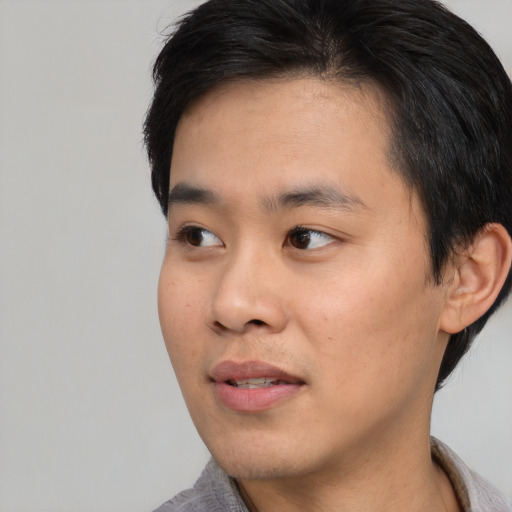 Joyful asian young-adult male with short  black hair and brown eyes