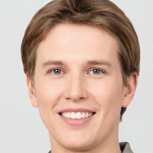 Joyful white young-adult male with short  brown hair and grey eyes