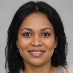 Joyful black young-adult female with long  brown hair and brown eyes